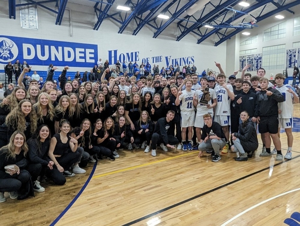 the boys basketball team and supporters grinning on the court